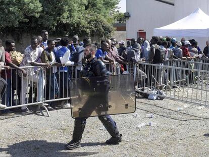 Un policía, ante una fila de inmigrantes en Nantes (Francia).