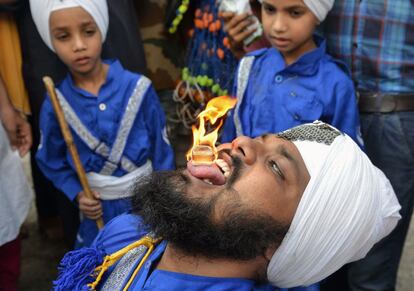 Un indio 'nihang', un guerrero religioso, sostiene un cubo ardiendo en la boca con motivo de una procesión que celebra el 413 aniversario de la proclamación del gurú Granth Sahib en el Templo Dorado, en Amritsar (India).