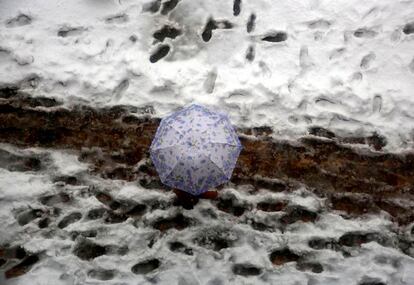 Una persona camina sobre la nieve y bajo un paraguas en Srinagar (India), en medio de una intensa ola de frío.