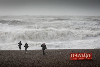 Un grupo de gente camina en la playa de Brighton, Inglaterra, este viernes. La Oficina Meteorológica del Reino Unido ha emitido hoy dos avisos meteorológicos rojos para el sur y el sudoeste de Inglaterra. Gran parte del país está bajo advertencias naranjas y amarillas.