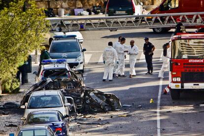 Agentes de la policía y bomberos junto al vehículo de la Guardia Civil destrozado por una bomba colocada por ETA, en Mallorca, el 30 de julio de 2009.