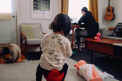 Una madre trabaja, mientras su hija juega en el salón.