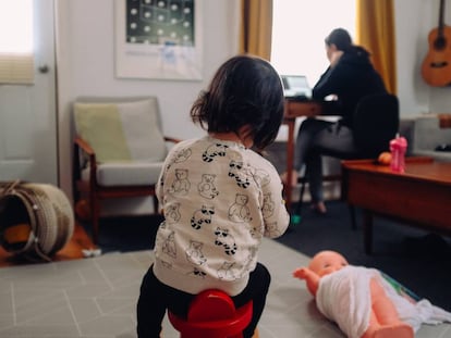 Una madre trabaja, mientras su hija juega en el salón.