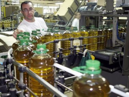 Un empleado supervisa la cadena de envasado de aceite de oliva.