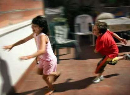 Dos niños se divierten correteando en la terraza de su casa.