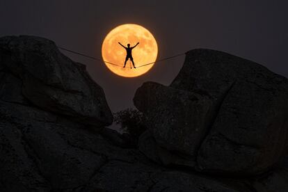 Un equilibrista fotografiado por la noche con la luna de fondo