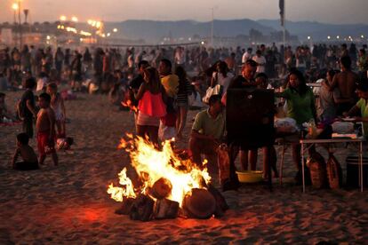 Un grupo de personas prepara una barbacoa junto a una hoguera, esta noche en la playa de la Malvarrosa de Valencia, donde cada noche de San Juan.