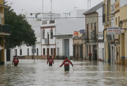 Un grupo de bomberos inspecciona ayer la calle Lepanto, inundada por la riada, en la localidad sevillana de Lora del Río.