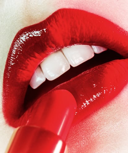 Se delinea el contorno del labio y se rellena con el perfilador Fabulous Kiss Lip Liner (tono Carolina Red, 310) y a continuación se aplica una dosis de extrabrillo con el labial líquido de efecto vinilo Good Girl (tono Red Carolina, 310), todo de HERRERA BEAUTY.