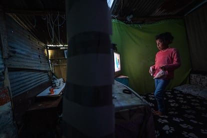  Isleni paga a un vecino y una vecina por la conexión clandestina que tiene a la electricidad y al sistema de agua, respectivamente. En la imagen, una de sus hijas ve la televisión.