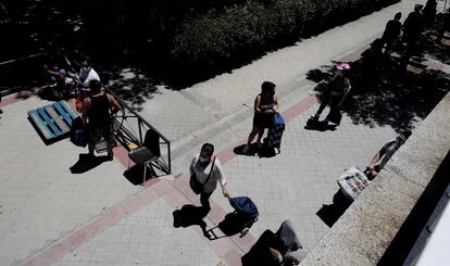 Colas de personas esperan a las puertas de la Parroquia Santa María Micaela (Madrid) para recibir una ayuda alimentaria.