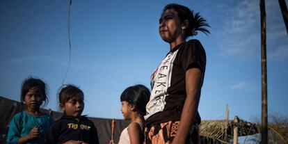 Una mujer y unos niños se paran frente a una tienda de campaña en un refugio temporal.