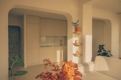 La cocina se cambió de orientación y ahora mira hacia la zona de día. Antes estaba en el acceso, a modo de pasillo. Marta Miñarro diseñó dos pórticos que marcan el salón y el comedor. Esto le sirvió para dar soporte espacial al sofá, hecho a medida para ocultar una viga que pasa por debajo. También, para recrecer un pilar y crear una estantería.