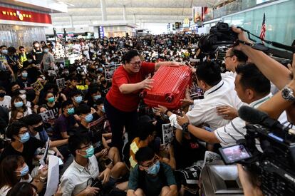 Una turista da su equipaje a los guardias de seguridad mientras trata de acceder a la zona de salidas del aeropuerto de Hong Kong, el 13 de agosto de 2019.