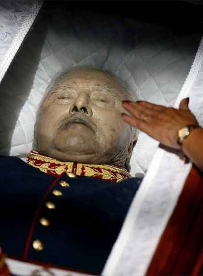Una partidaria de Pinochet toca el vidrio que cubría su cadáver.