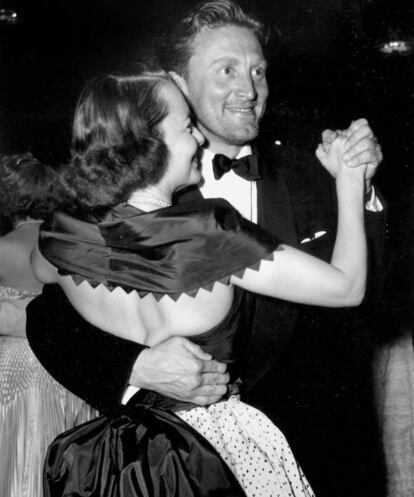 Quién les iba a decir a Olivia de Havilland y Kirk Douglas mientras bailaban agarrados durante el Festival de Cannes de 1953 (en la imagen) que 53 años más tarde cumplirían 100 años (ella el pasado 1 de julio) convertidos en los últimos supervivientes del Hollywood clásico. Ambos tienen mucho más en común que sus años de nacimiento: los dos pusieron de rodillas a Hollywood y destruyeron los cimientos de una industria esclavista con sus estrellas. Tras dar su primer pelotazo como actor, Douglas se negó a firmar el contrato estándar de siete años según el cual los actores estaban obligados a aceptar todos los proyectos que el estudio quisiera. Él valoraba su libertad por encima de todo, y revolucionó la industria convirtiéndose en la primera estrella en fundar su propia productora. Olivia De Havilland también se rebeló contra el sistema cuando llevó a la Warner a juicio, cuya resolución engendró la 'Ley De Havilland', que puso fin definitivamente a la esclavitud de las estrellas.