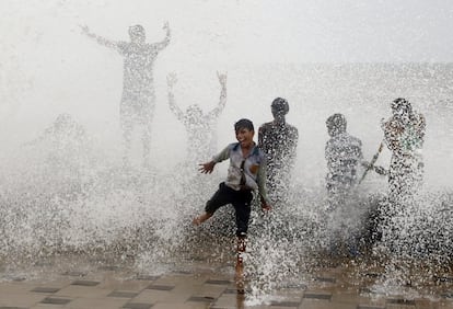 Niños indios se empapan con las olas que golpean la costa durante la marea Arábigo en Mumbai, India.