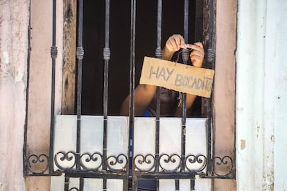 A woman hangs a sign advertising food in Havana.