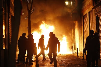 Contenedores incendiados en la calle Mesón de Paredes con la calle del Oso, en el barrio de Lavapiés de Madrid.