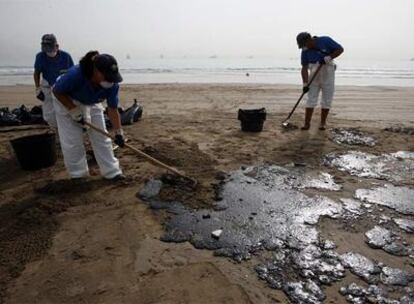 Tres trabajadores limpiaban ayer la playa de Getares.