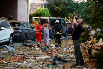 Personal de emergencia asiste a una mujer en una zona afectada por  un ataque ruso en Kiev.