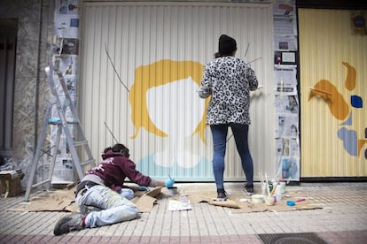 Mosto en Vena e Iracema son los nombres artísticos de Elena González (en el suelo) y Florencia Olivera. La primera interviene los edificios de adobe del pueblo segoviano en el que vive, es DJ y canta. "Cojo una jota extremeña y me la llevo al <i>trip-hop",</i> ilustra. Iracema reside en Segovia capital y trabaja como pintora de brocha gorda con una cuadrilla de albañiles. La silueta de mujer que emerge en el garaje acabará convirtiéndose, en solo tres días, en una metáfora de los brotes verdes o en un simple laurel. Todo depende del color con el que se mire.