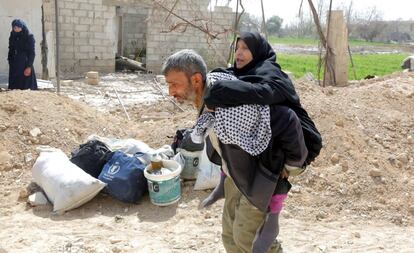 Un hombre sirio lleva a su madre en brazos, mientras abandonan, junto a cientos de civiles, la zona de Guta Oriental, en la zona rural de Damasco (Siria), el 15 de marzo de 2018. 