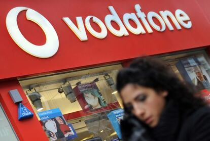 Un transeúnte camina frente a una tienda de Vodafone.