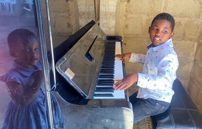 Delbert, niño disléxico que nació y vive en Arusha, Tanzania, toca el piano en la Iglesia Adventista del Séptimo Día, a la que acude cada sábado con su familia. En el reflejo, una amiga suya.