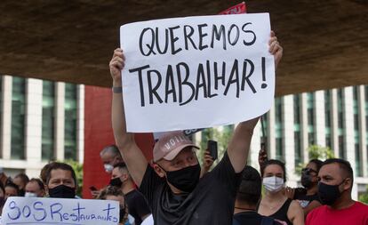 Un trabajador de un restaurate sostiene un letrero con la leyenda "Queremos trabajar", el 27 de enero.