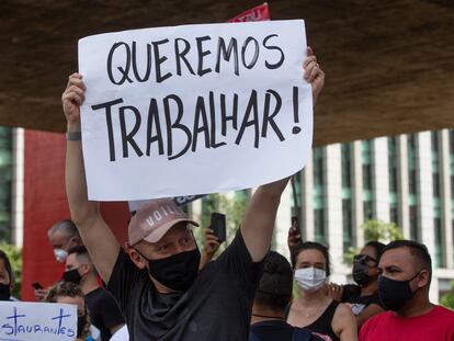 Un trabajador de un restaurate sostiene un letrero con la leyenda "Queremos trabajar", el 27 de enero.