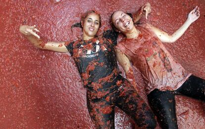 Dos jóvenes participantes en la Tomatina tumbadas en el suelo, en la localidad valenciana de Buñol.