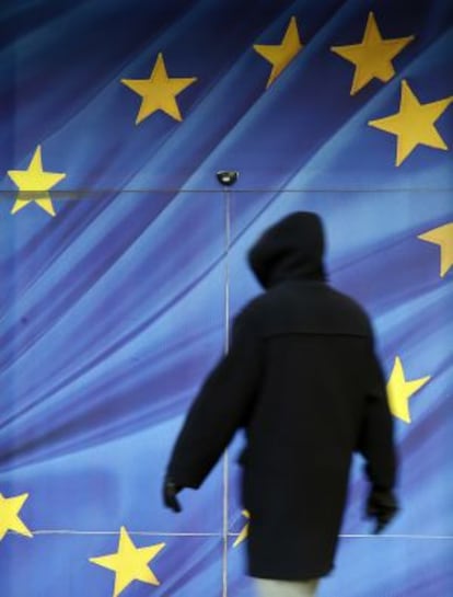 Un ciudadano pasea junto a la bandera de la UE de la fachada de la Comisión Europea, en Bruselas.