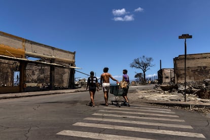 Unos residentes transportan un carrito entre las ruinas de los edificios quemados por el incendio, este viernes en Lahaina (Hawái). 
