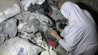 Una mujer toca el cadáver de un hombre atrapado entre los escombros de una escuela tras un bombardeo israelí sobre Gaza, este martes.