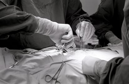 Two hands are visible performing surgery on a patient.