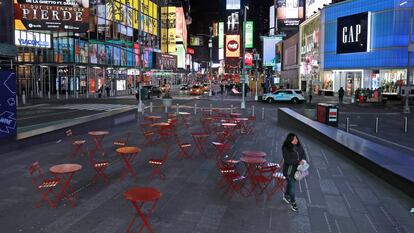 Mulher trafega em uma Times Square quase vazia, em Nova York, na noite de segunda.