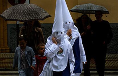 Dos nazarenos de la hermandad de Los Negritos, una de las cinco cofradías que decidieron no salir ayer en Sevilla por la lluvia.