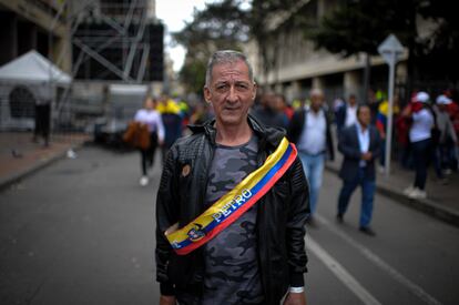 Un hombre posa para un retrato utilizando una banda con la bandera colombiana.