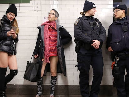 Dos participantes del 'No Pants Subway Ride' esperan el metro junto a dos policías.