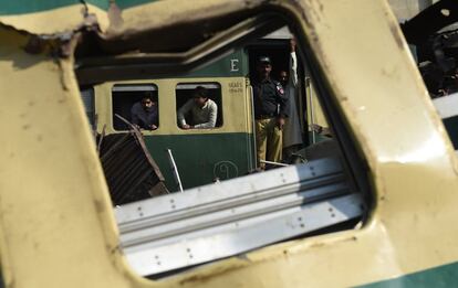 Pasajeros de un tren miran a los trabajadores reparar la vía en el lugar de una colisión entre dos trenes en Karachi (Pakistán). Al menos veinte personas han muerto y docenas han resultado heridas.