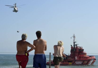 Varios bañistas observan este jueves en Valencia unas prácticas de salvamento marítimo.