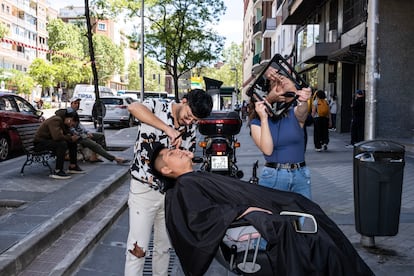 David Alexandre le corta el pelo a Leandro Carvajal en la calle del Ferrocarril.