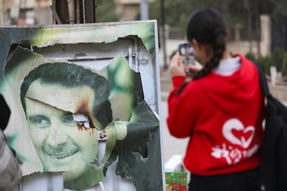 Uma mulher tira uma fotografia de um cartaz rasgado de Bashar al-Assad, neste domingo, em Qamishli, na Síria.