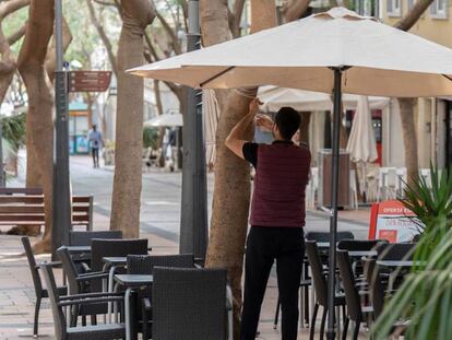 Un camarero coloca una sombrilla en la terraza de un bar en Santa Cruz de Tenerife. 