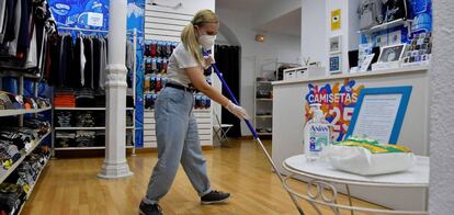 Una chica limpia una una tienda de camisetas en Almería.