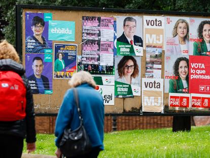 Dos personas pasan frente a unos carteles electorales en Bilbao.