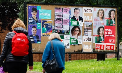 Dos personas pasan frente a unos carteles electorales en Bilbao.