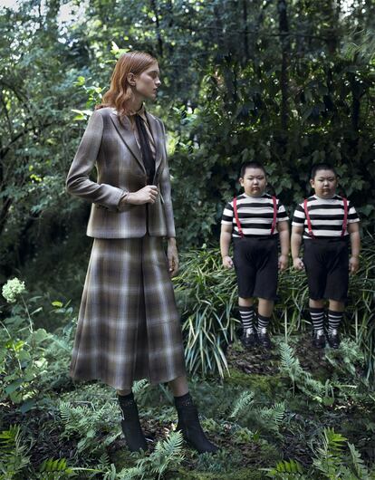 Dee y Tweedle Dum Traje de chaqueta y falda midi evasé de lana con estampado de cuadros británicos marrones y blancos, blusa de seda, corbata y calcetines negros, todo de Dior; y botines de ante con hebillas de strass de Mascaró.