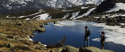 Unos senderistas observan la laguna de Peñalara.